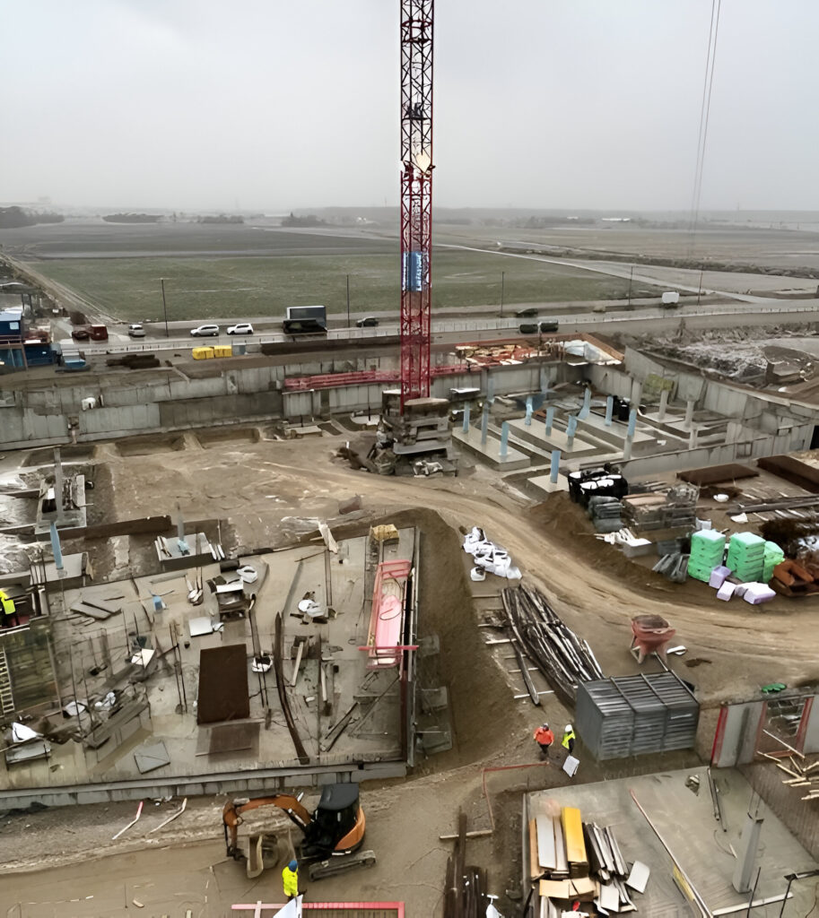 Industrie-Baustelle mit Kran, Baugrube und schwerem Gerät.